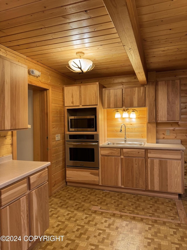 kitchen with sink, wooden walls, beamed ceiling, wood ceiling, and stainless steel appliances