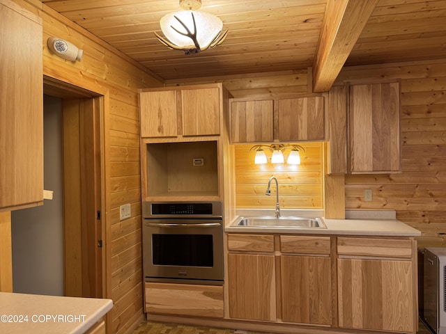 kitchen featuring wood walls, stainless steel oven, wooden ceiling, and sink