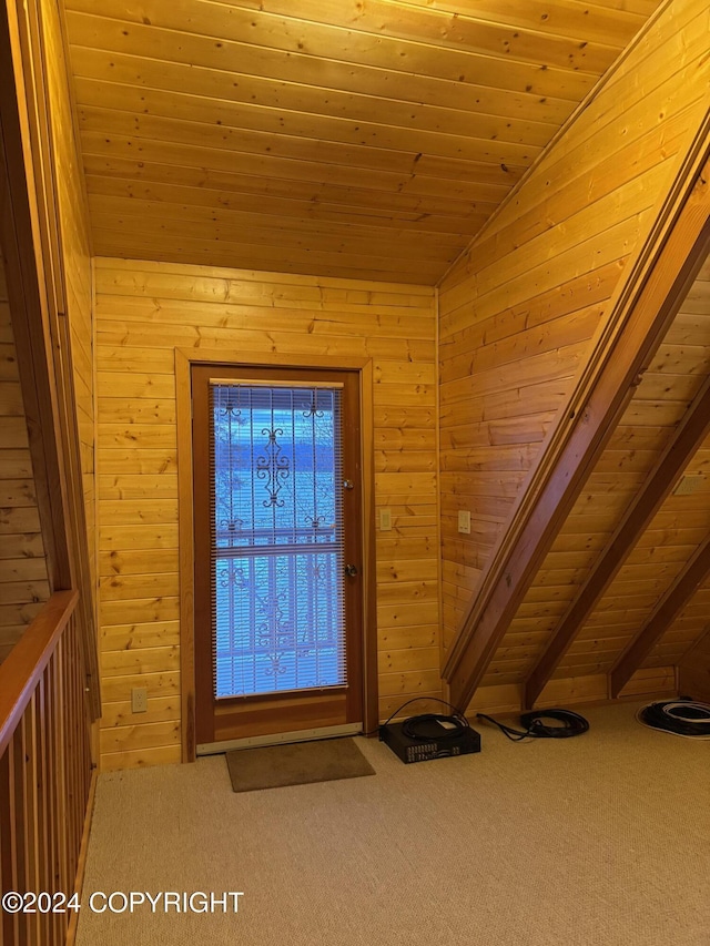 entrance foyer with carpet flooring, lofted ceiling with beams, wooden walls, and wood ceiling