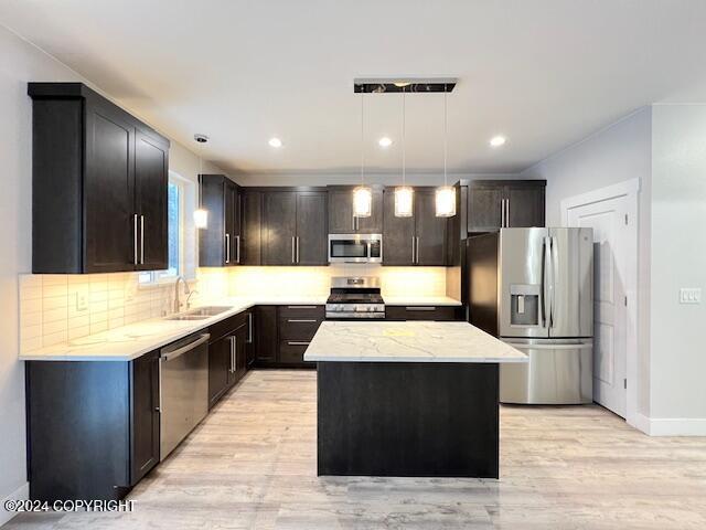 kitchen featuring pendant lighting, a center island, sink, light hardwood / wood-style flooring, and stainless steel appliances