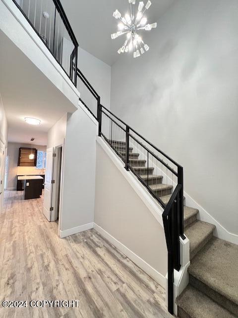 stairway with wood-type flooring and a notable chandelier