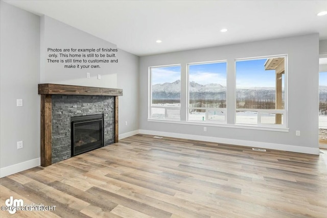 unfurnished living room with a stone fireplace and light hardwood / wood-style flooring