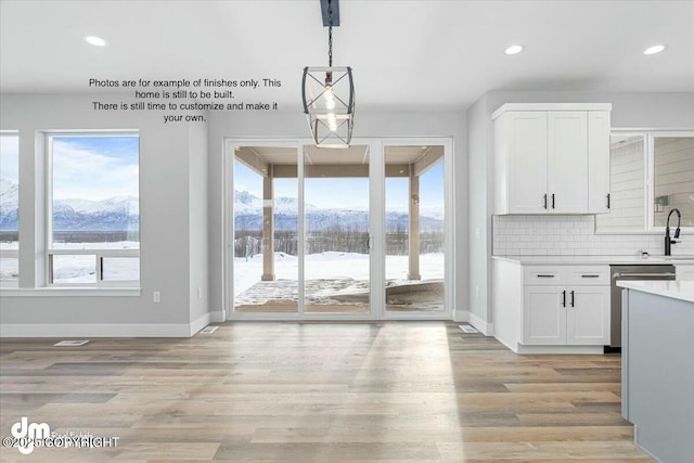 unfurnished dining area with a mountain view, a wealth of natural light, sink, and light wood-type flooring