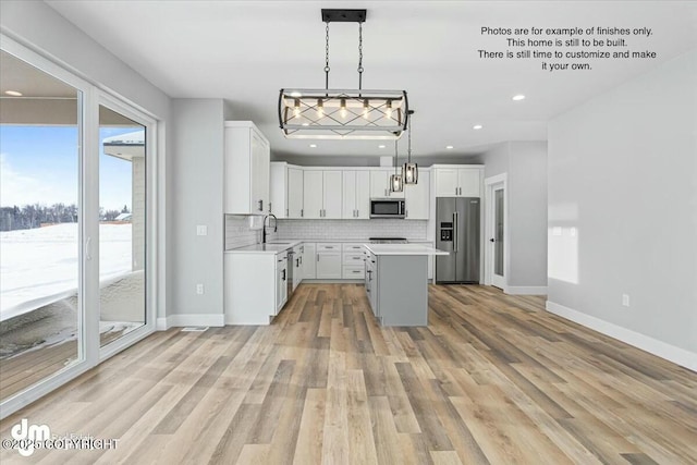 kitchen with pendant lighting, appliances with stainless steel finishes, white cabinetry, a center island, and decorative backsplash