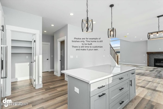 kitchen featuring gray cabinets, a kitchen island, pendant lighting, and light wood-type flooring