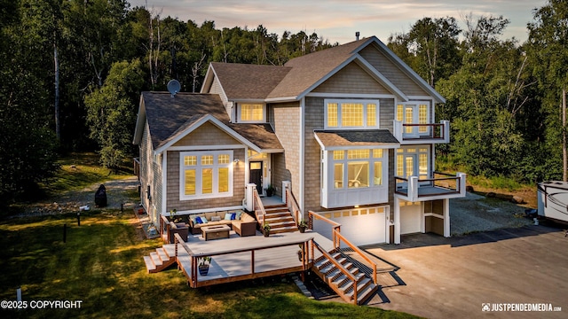 view of front of house featuring a balcony, a deck, outdoor lounge area, a garage, and a lawn