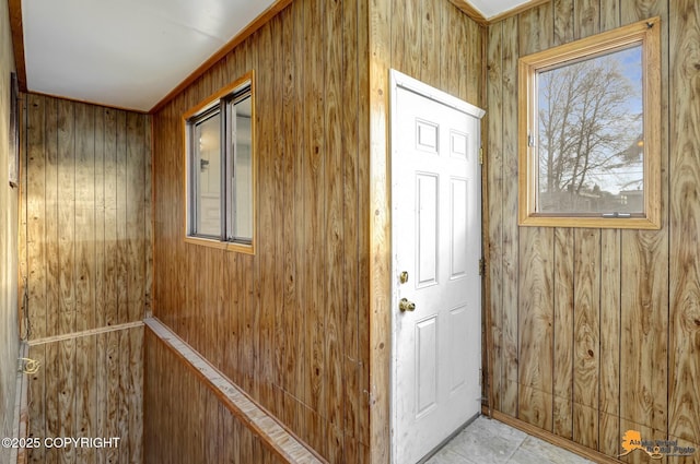 doorway featuring tile patterned floors and wood walls