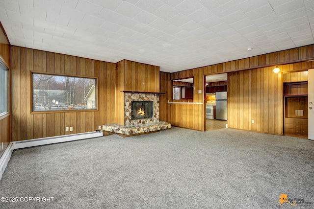 unfurnished living room with a baseboard radiator, carpet, wood walls, and a fireplace