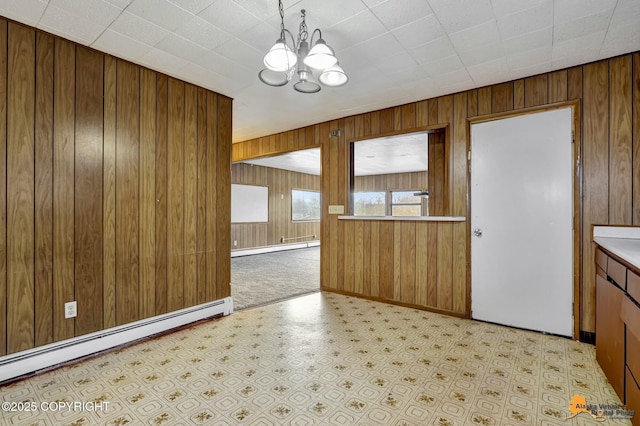 interior space featuring a baseboard radiator, wooden walls, and a notable chandelier