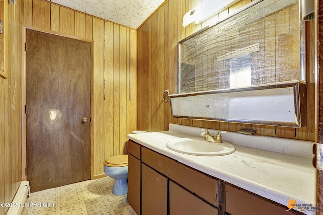 half bath with vanity, wood walls, a baseboard heating unit, tile patterned floors, and toilet