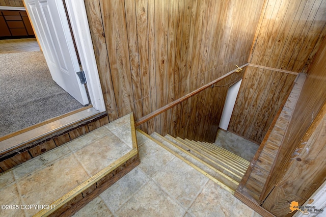 stairway featuring wooden walls