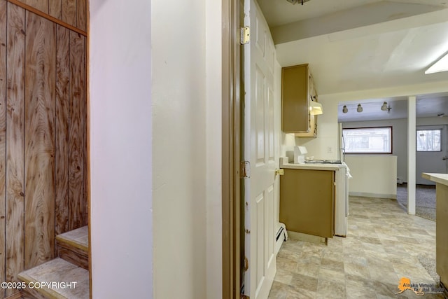 kitchen with under cabinet range hood, a baseboard heating unit, and light countertops