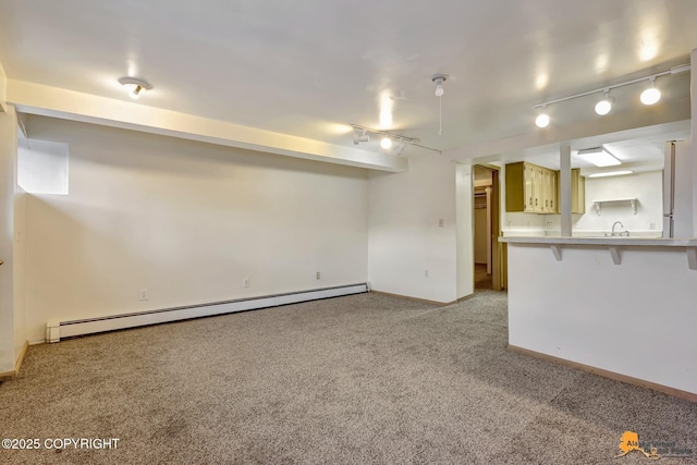 unfurnished living room featuring light carpet, track lighting, a sink, baseboards, and baseboard heating