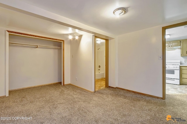 unfurnished bedroom featuring a closet, light colored carpet, ensuite bathroom, and baseboards