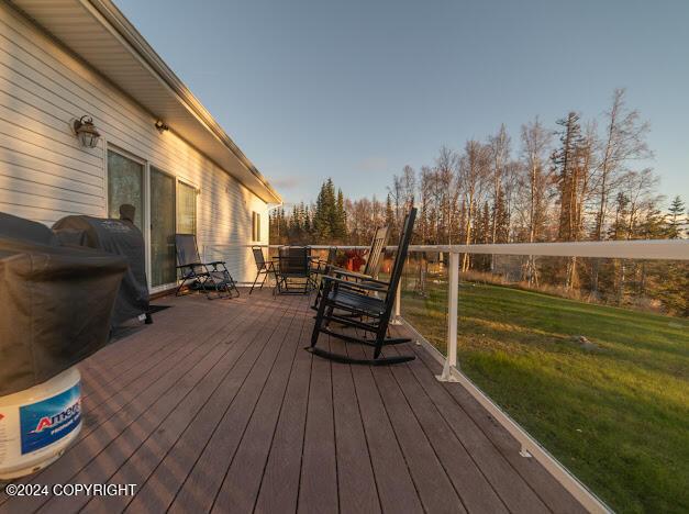 deck at dusk featuring a lawn