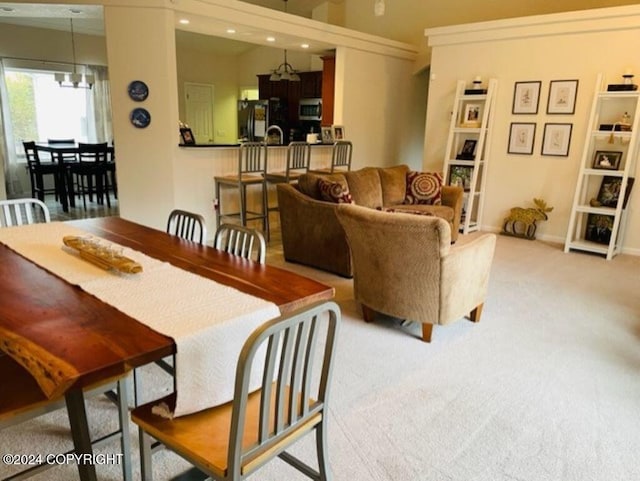 dining area featuring light carpet and a chandelier