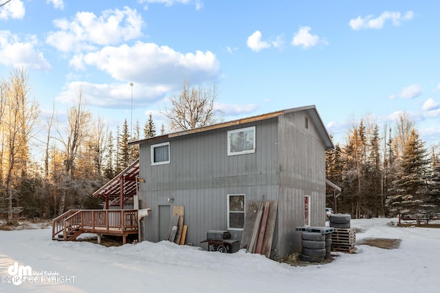 snow covered back of property with cooling unit and a deck