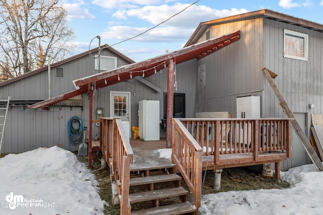 snow covered back of property featuring a deck