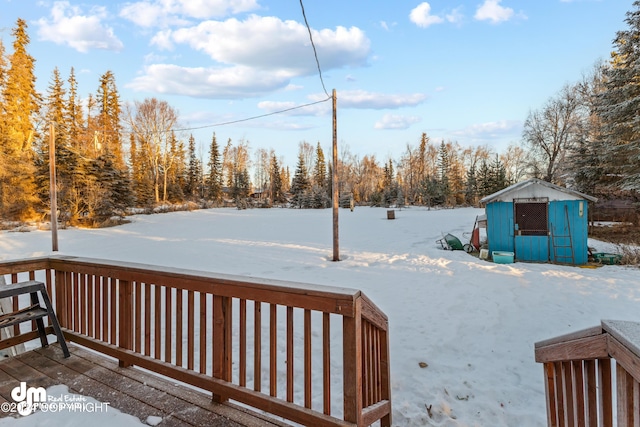 yard covered in snow with a shed and a wooden deck