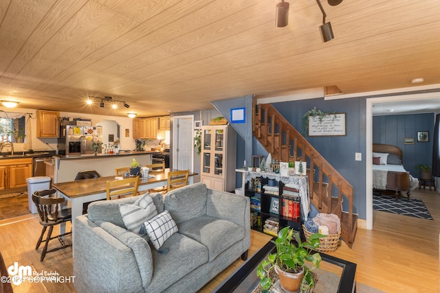 living room with light wood-type flooring, rail lighting, wooden ceiling, and sink