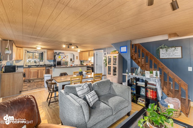 living room featuring sink, wooden ceiling, track lighting, wooden walls, and light wood-type flooring