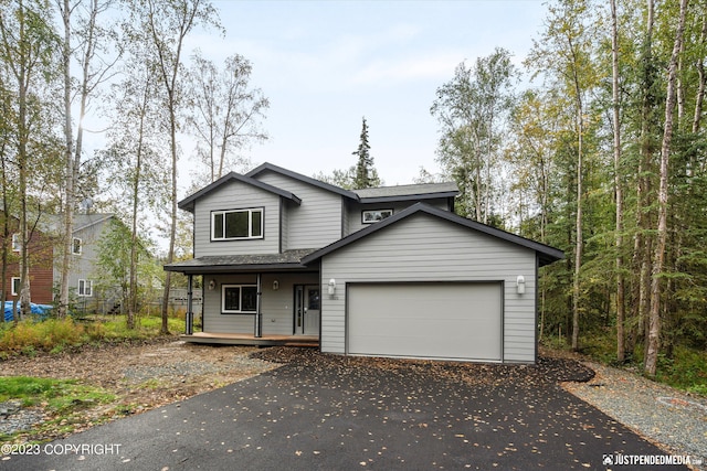 view of front of home with a porch, asphalt driveway, an attached garage, and a shingled roof