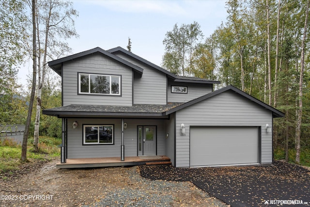 view of front facade featuring a porch, driveway, an attached garage, and roof with shingles