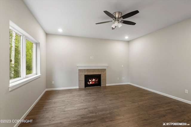 unfurnished living room featuring a tiled fireplace, a ceiling fan, dark wood-type flooring, baseboards, and recessed lighting