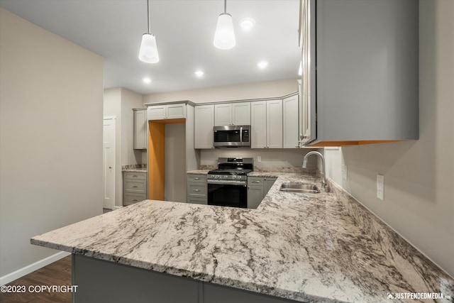 kitchen with stainless steel appliances, a sink, light stone countertops, baseboards, and a peninsula