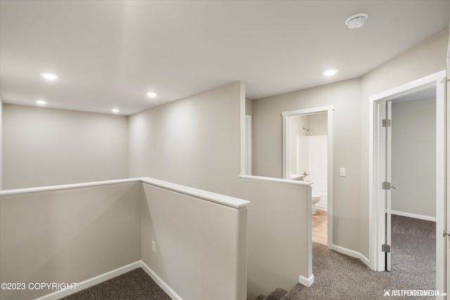 corridor featuring carpet floors, an upstairs landing, recessed lighting, and baseboards