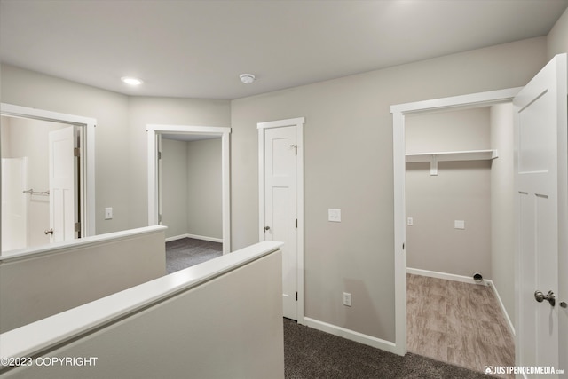 hallway with dark colored carpet, baseboards, and recessed lighting