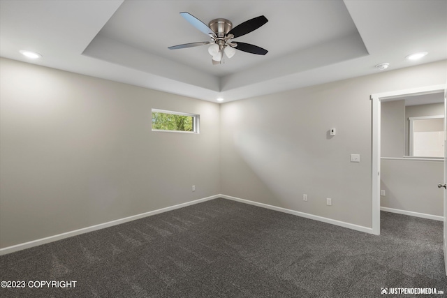 unfurnished room with ceiling fan, dark colored carpet, a raised ceiling, baseboards, and recessed lighting