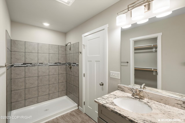 full bathroom with tiled shower, vanity, wood finished floors, and recessed lighting