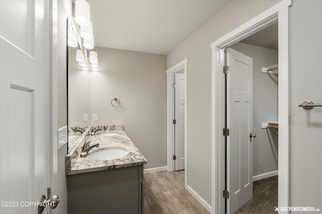 bathroom featuring double vanity, baseboards, and wood finished floors
