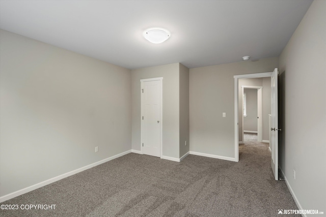 unfurnished bedroom featuring dark colored carpet and baseboards