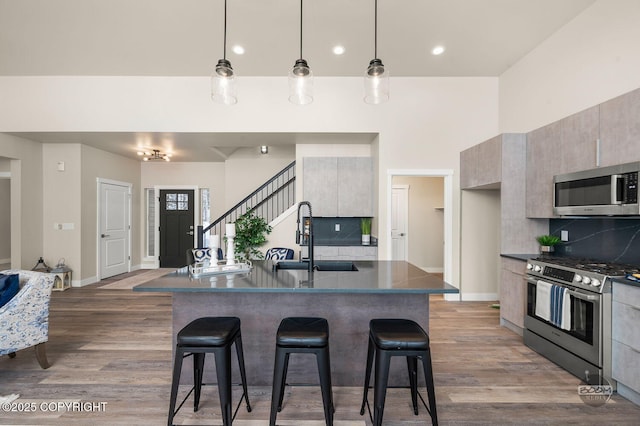 kitchen featuring a kitchen breakfast bar, sink, appliances with stainless steel finishes, and tasteful backsplash