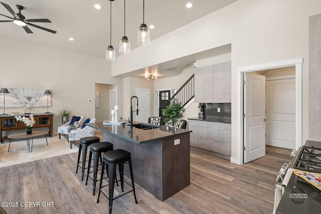 kitchen featuring stainless steel range, a breakfast bar, ceiling fan, sink, and decorative light fixtures