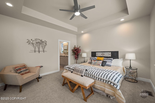 carpeted bedroom with ceiling fan, a raised ceiling, and connected bathroom