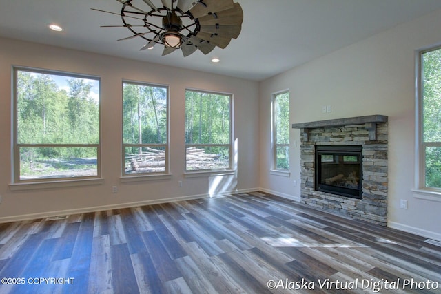 unfurnished living room with ceiling fan, a healthy amount of sunlight, wood-type flooring, and a fireplace