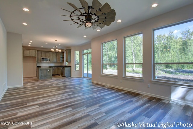 unfurnished living room featuring dark hardwood / wood-style floors, a wealth of natural light, and a notable chandelier