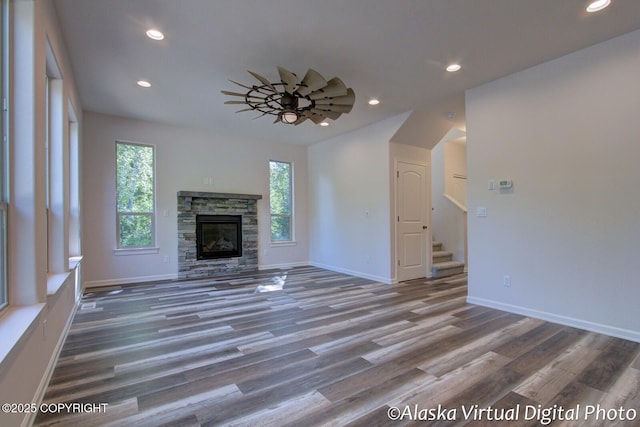 unfurnished living room featuring ceiling fan, a fireplace, and dark wood-type flooring