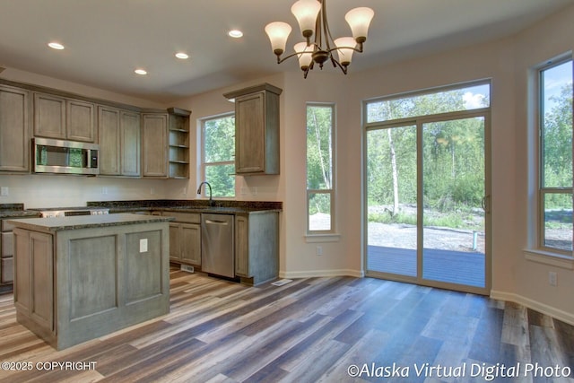 kitchen featuring appliances with stainless steel finishes, pendant lighting, wood-type flooring, a chandelier, and a kitchen island