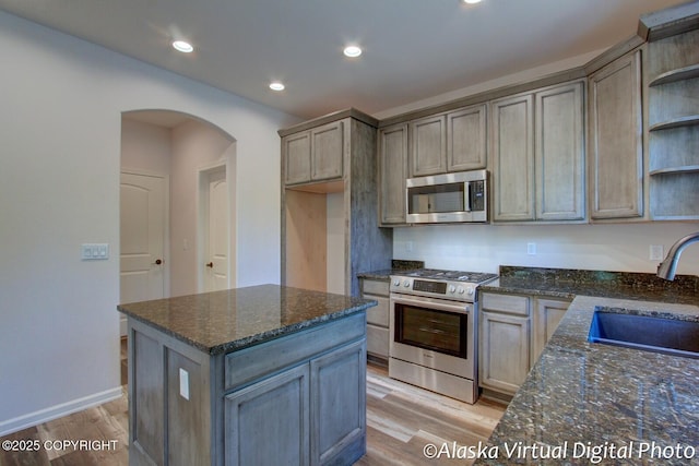 kitchen featuring dark stone countertops, sink, stainless steel appliances, and light wood-type flooring