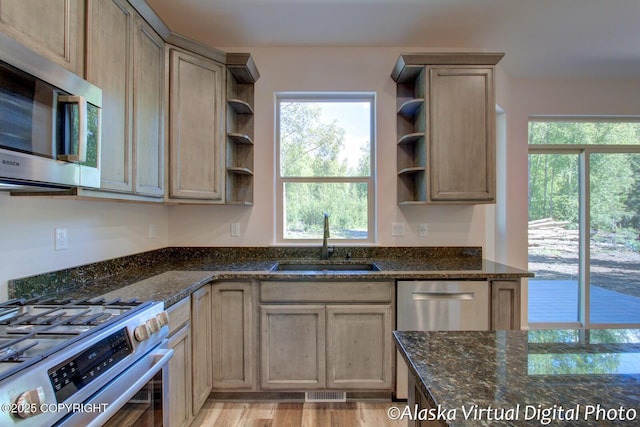 kitchen with light hardwood / wood-style floors, sink, appliances with stainless steel finishes, and dark stone counters