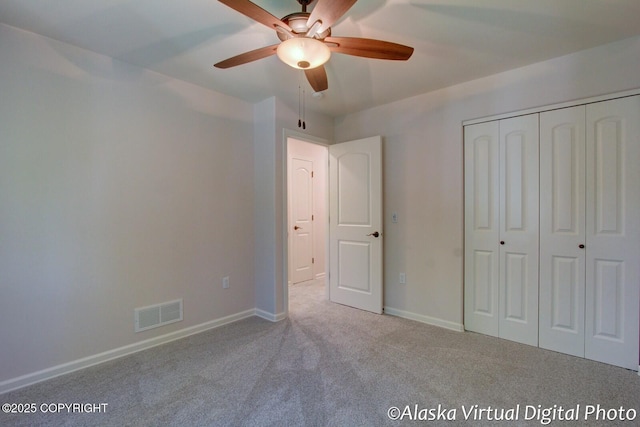 unfurnished bedroom featuring a closet, light colored carpet, and ceiling fan