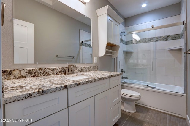 full bathroom with shower / bath combination with glass door, vanity, and toilet