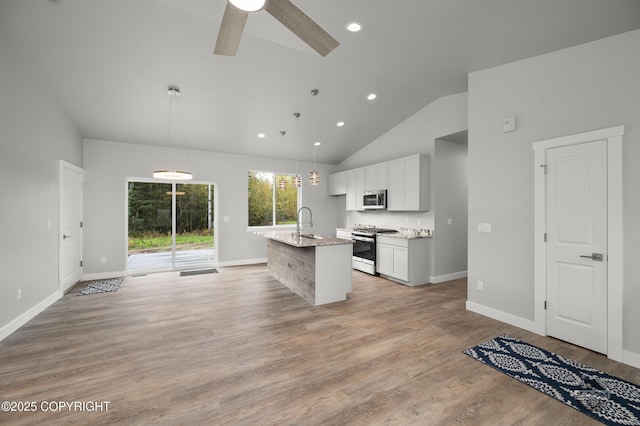 L12 Jasmine Rd, Chugiak, AK 99567 - kitchen with stainless steel microwave, range with gas stovetop, white cabinetry, an island with sink, and hanging light fixtures