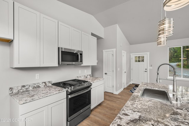 L12 Jasmine Rd, Chugiak, AK 99567 - kitchen with appliances with stainless steel finishes, a sink, lofted ceiling, white cabinetry, and light stone countertops