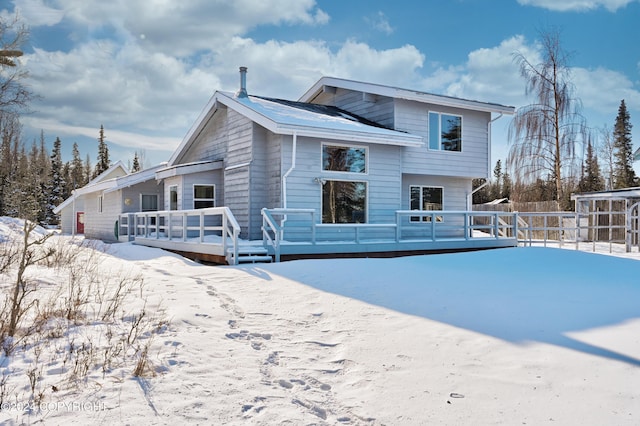 snow covered rear of property with a deck