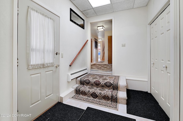 doorway to outside featuring a drop ceiling, light tile patterned flooring, and a baseboard radiator